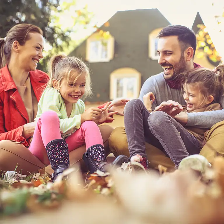 Family playing in the leaves in front of their house | Springer Professional Homes Services in Des Moines, Iowa
