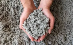 Two hands holding a handful of cellulose insulation